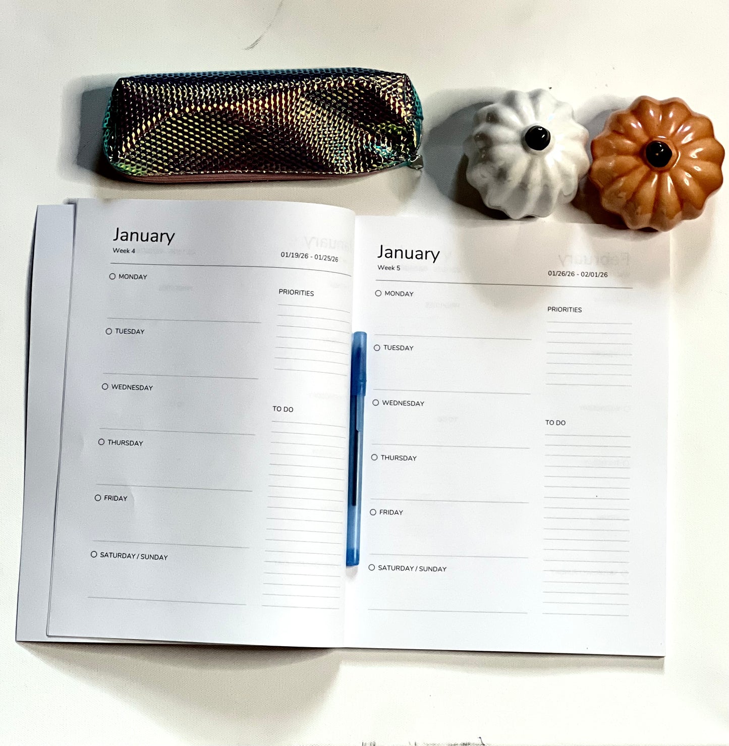 Open planner with January schedule on a white surface with decorative items.