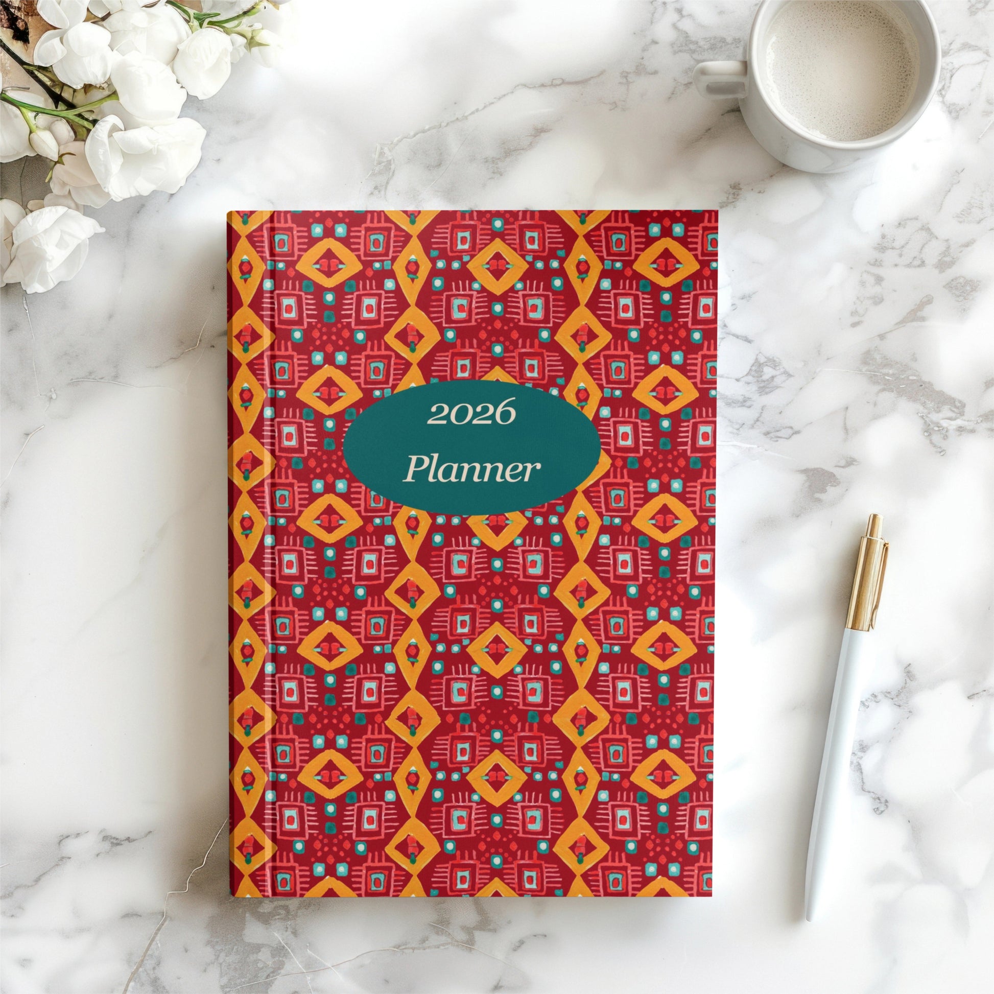 2026 planner with geometric pattern on a marble surface with flowers and a pen.